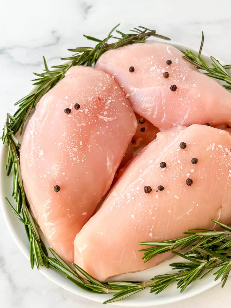raw chicken breast with salt and peppercorns